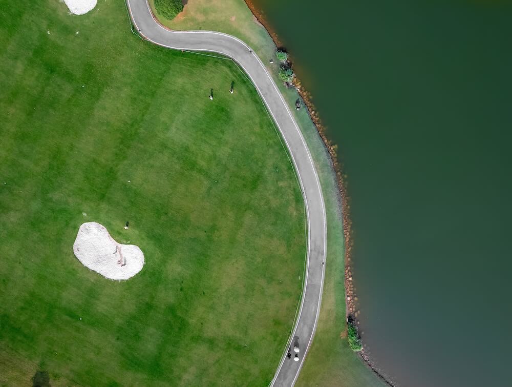 Aerial View of a Golf Course with Water and Curved Pathway