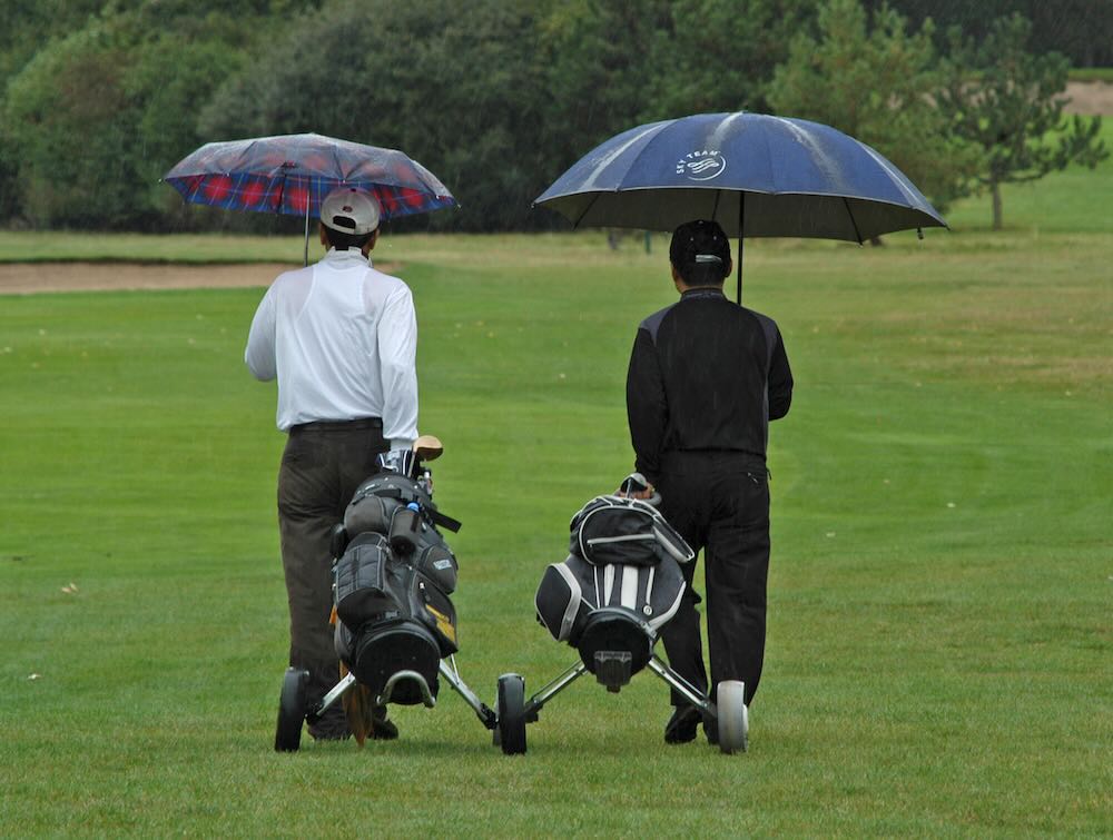Two golfers playing in a rain 
